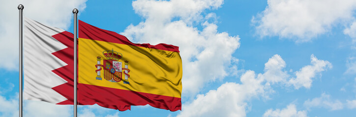 Fototapeta premium Bahrain and Spain flag waving in the wind against white cloudy blue sky together. Diplomacy concept, international relations.
