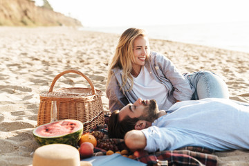 Cheerful young couple in love having picnic - obrazy, fototapety, plakaty