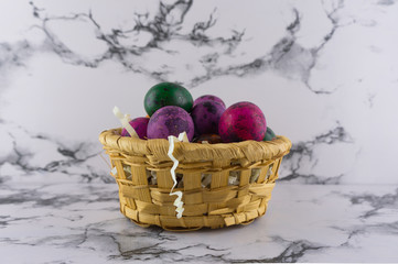 Marble Easter background with painted quail Easter eggs in a wicker basket.