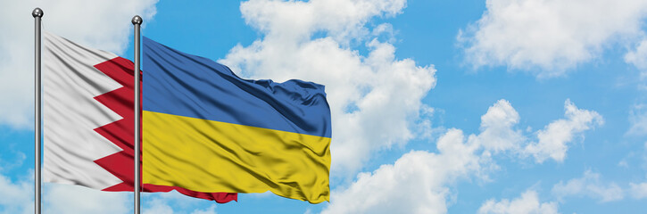 Bahrain and Ukraine flag waving in the wind against white cloudy blue sky together. Diplomacy concept, international relations.