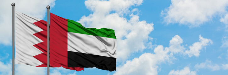 Fototapeta na wymiar Bahrain and United Arab Emirates flag waving in the wind against white cloudy blue sky together. Diplomacy concept, international relations.