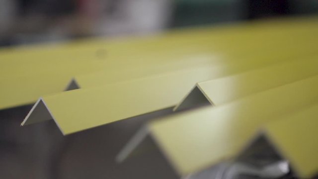 Multiple yellow painted L-Profile steel bar. Footage from the inside of a metal factory. Slow motion. 