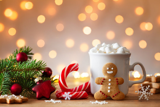 Cozy wintertime scene. Gingerbread man, cup of hot cocoa with marshmallow and Christmas fir branch.