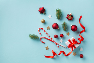 Creative Christmas composition made of gift box and holiday decorations on blue background top view. New Year greeting card. Flat lay.