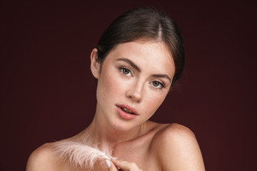 Image of half-naked woman holding feather and looking at camera