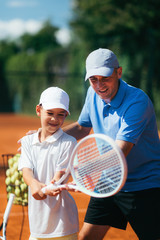 Tennis Lesson. Smiling Coach Explaining Tennis Technique to a Boy