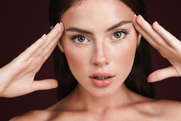 Image of half-naked woman touching her temples and looking at camera