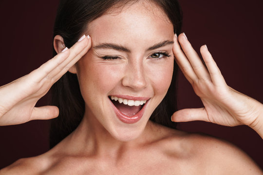 Image of smiling half-naked woman touching her temples and winking