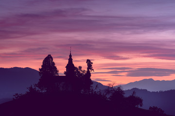 Fototapeta premium A beautiful shot of s silhouette of a church in the mountains and the pink sunset sky in the background. Great for desktop wallpaper and backgrounds
