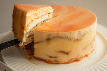 A piece of orange mirror glazed cake with cream cheese filling and nuts. Italian Nuts Cake.