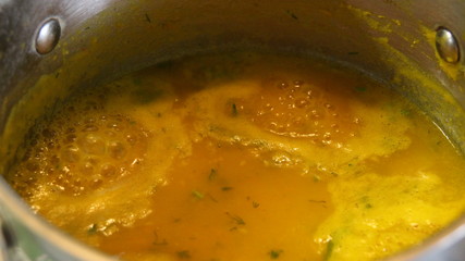 gurgling, boiling orange pumpkin soup in metal pan