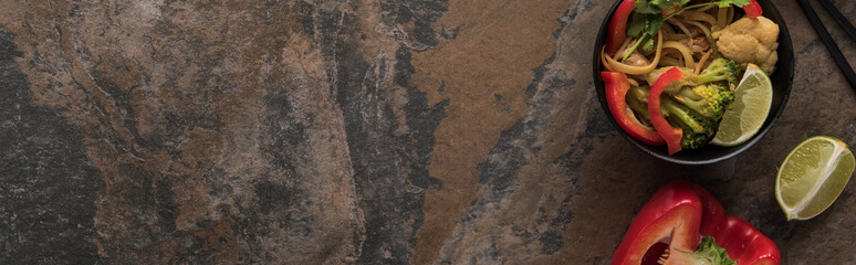top view of thai noodles with vegetables near chopsticks on stone surface, panoramic shot