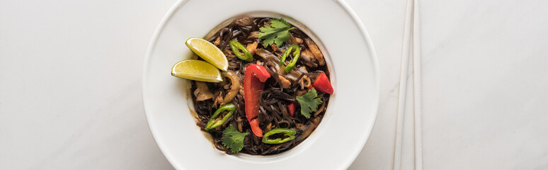 top view of delicious meat thai noodles with chopsticks on marble grey surface, panoramic shot