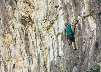 Man with a rope engaged in the sports of rock climbing on the rock.