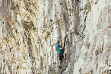 Man with a rope engaged in the sports of rock climbing on the rock.