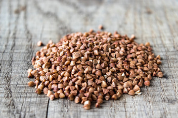 A pile of uncooked buckwheat scattered on old boards. Buckwheat is used for cooking.