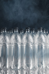 empty plastic bottles on black background with smoke, pollution concept