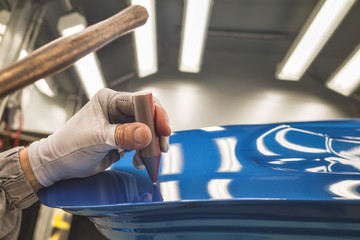 Employee car body painting shop eliminates a small metal defect