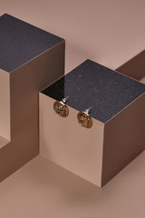 Object photo of a mother-of-pearl half-ball stud earrings, located on a dark beige cube with black...