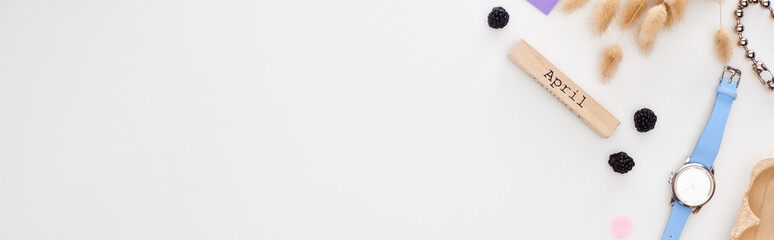 panoramic shot of wooden block with april inscription, spikelets, blackberry, wristwatch, bracelet...
