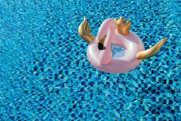 Glamorous pink and gold swan / flamingo pool float in blue swimming pool with copy space