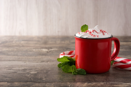 Peppermint coffee mocha decorated with candy canes for Christmas on wooden table Copy space