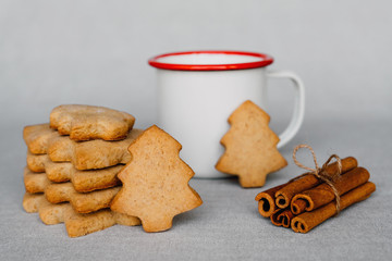 Stack of delicious homemade cookies in the shape of Christmas tree and cup of hot drink.