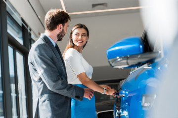 bearded man standing with attractive woman near blue car