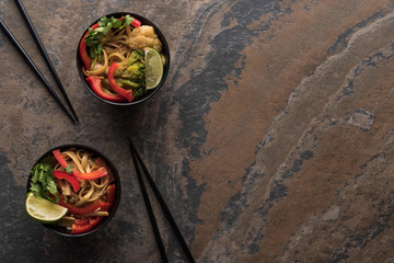 top view of tasty spicy thai noodles with chopsticks on stone surface