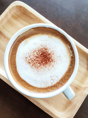 A cup of coffee is placed on a wooden tray.