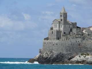 Fototapeta na wymiar Church of San PIetro in Portovenere, built on a rock overlooking the sea. Sky with clouds and blue sea waves.