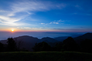 Landscape scene of colorful sunrise sky and mist with mountain range and forest in thailand.