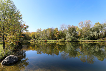 Autumn foliage and reflections on the water. Sunny , early fall afternoon on the waters edge.