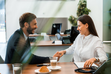 selective focus of happy man in suit and woman shaking hands