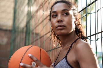 Image of african american woman playing basketball at playground