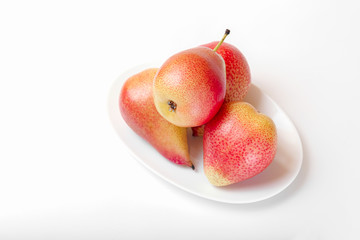 Three red-yellow pears on a white plate