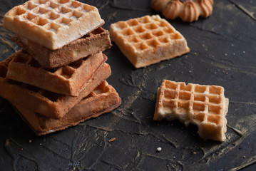 a stack of waffles on a black table, a bitten wafer,