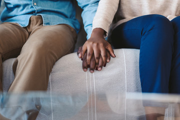 Young African American couple holding hands on a sofa