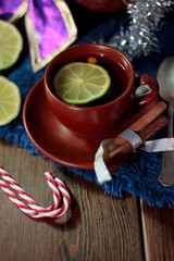 Nice christmas tea on wooden table with lime.