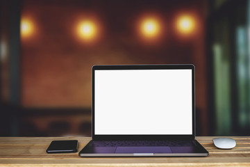 Laptop computer with blank white screen on the table, background wall blur