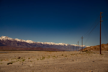 Wüste mit Strimleitung und im Hintergrund eine Bergkette mit weissen Gipfeln