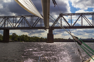 View of the railway bridge from the yacht. Part of the boom of the yacht. Storm clouds in the sky