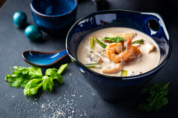 Tom Yum Kung soup, a Thai traditional spicy prawn soup in a bowl on dark background
