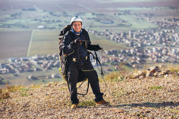 Senior paraglider on the ground prepairs to fly.