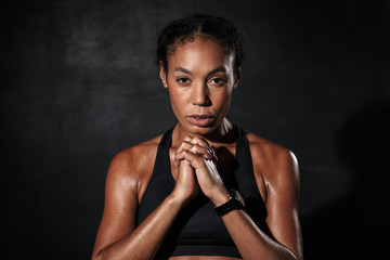 Image of strict african american woman standing with hands together
