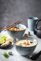 Tom Yum Kung soup, a Thai traditional spicy prawn soup in a bowl on gray background