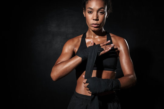 Image of african american woman in sportswear wearing boxing hand wraps
