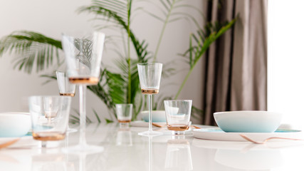 Close-up of served table in a luxury restaurant at the holiday eve. Serving dishes, glass wine glasses and gold cutlery.