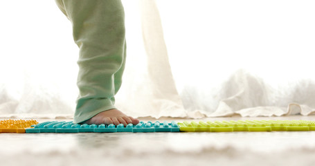 Child on massage mat doing exercises for flatfoot prevention at home