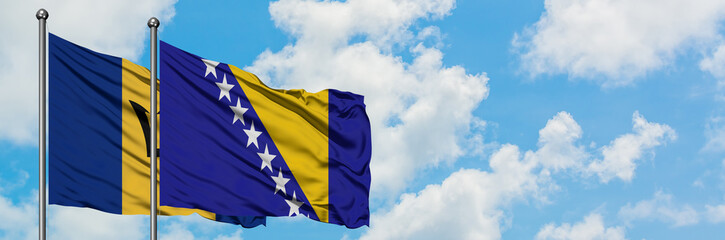 Barbados and Bosnia Herzegovina flag waving in the wind against white cloudy blue sky together. Diplomacy concept, international relations.